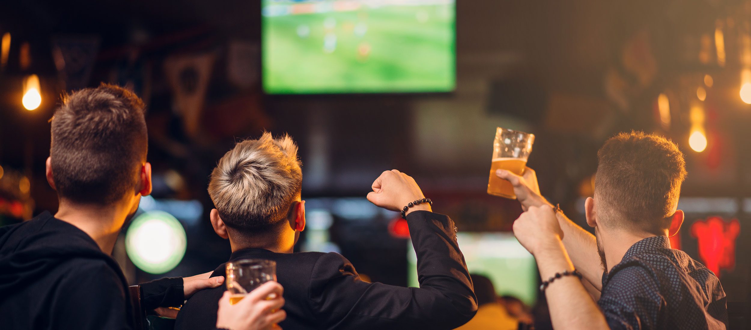 Men with beer cheering for sports on TV