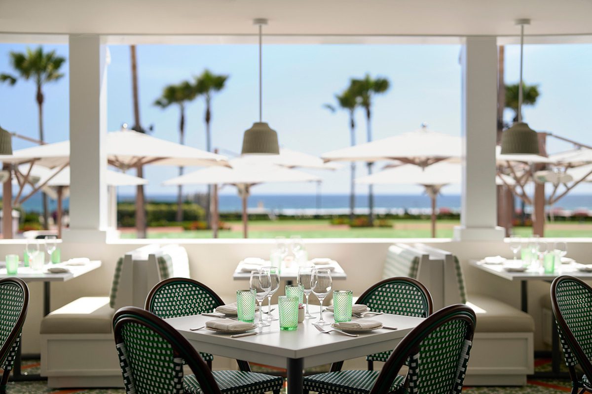 a table with cutlery and glasses set overlooking umbrellas and the ocean