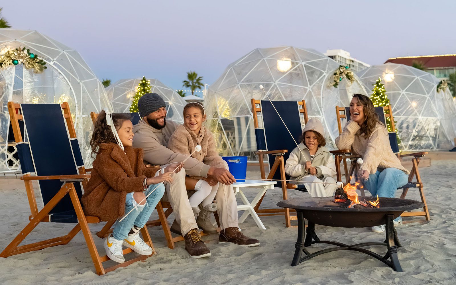 Family roasting s'mores at a Beach Igloo