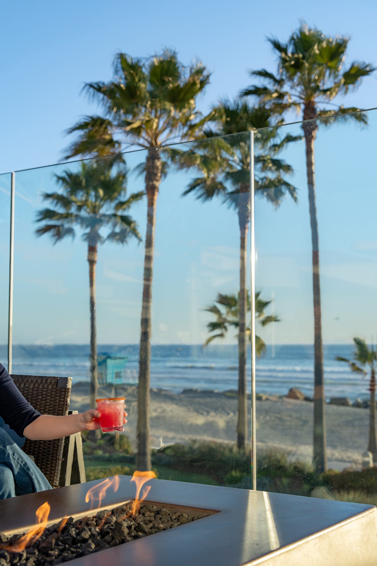 Woman holding a drink by a fire pit
